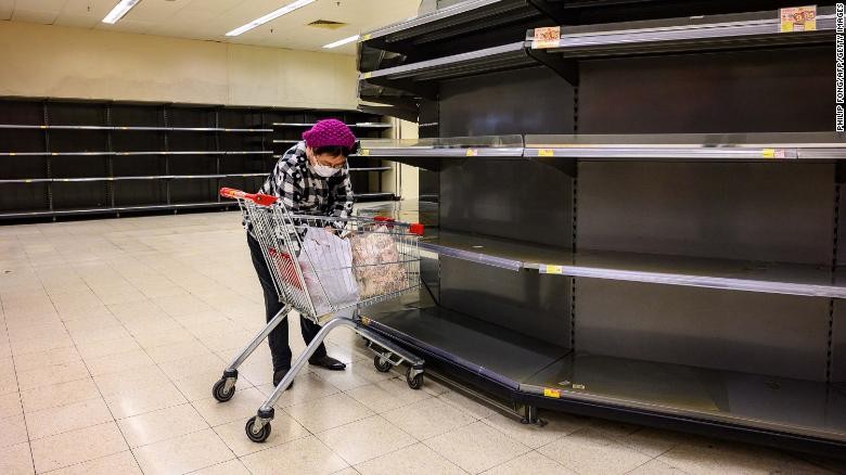 Một người dân đứng trước những kệ hàng sạch bong trong một siêu thị ở Hong Kong (Ảnh: CNN)