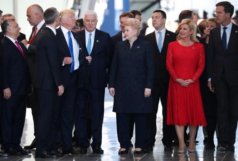 Ông Trump chỉnh lại áo khoác sau khi xô Thủ tướng Montenegro sang một bên (Ảnh: Reuters)