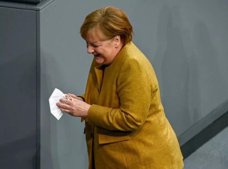 Bà Merkel cười sau khi lấy lại chiếc khẩu trang của mình từ bục phát biểu (Ảnh: Getty) Bà Merkel cười sau khi lấy lại chiếc khẩu trang của mình từ bục phát biểu (Ảnh: Getty)