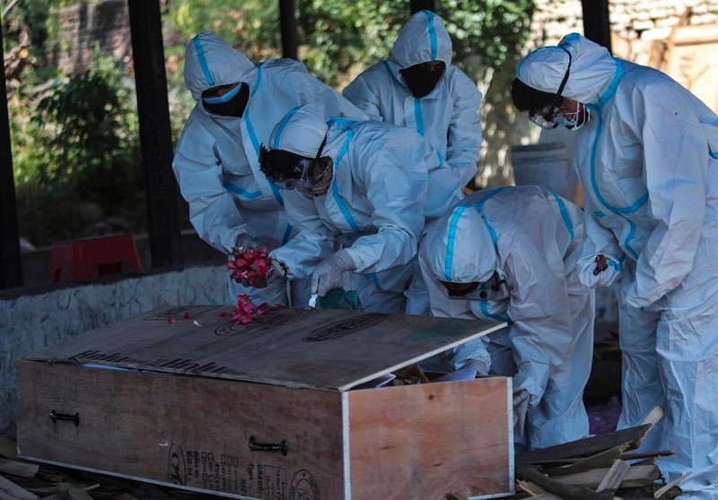 Thân nhân đặt hoa trên chiếc quan tài đơn sơ của bệnh nhân tử vong do COVID-19 trước khi tiến hành hỏa táng ở Jammu, ngày 25/4 (Ảnh: AP)