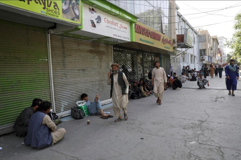 Người dân kéo nhau tới ngồi trước các cửa hàng đã đóng cửa để chờ rút tiền (Ảnh: AP)