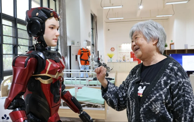 Một cư dân cao tuổi tại một viện dưỡng lão ở Thâm Quyến đang tương tác với một robot hình người. Ảnh: Xinhua.