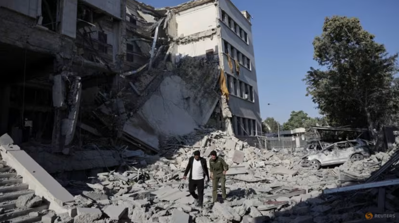 Người dân đi bộ giữa đống đổ nát sau cuộc không kích mạnh mẽ của Israel làm rung chuyển Damascus vào ngày 16/7. Ảnh: Reuters.