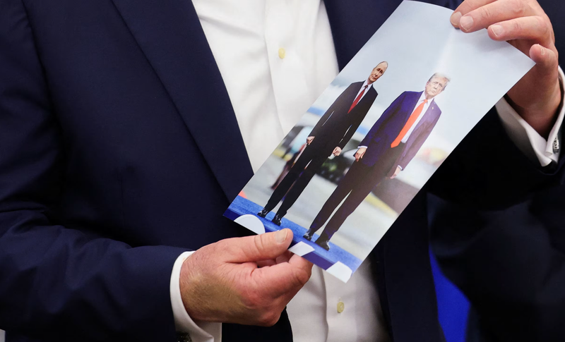 Tổng thống Mỹ Donald Trump cầm bức ảnh chụp ông và Tổng thống Nga Vladimir Putin trong cuộc gặp ở Alaska khi đang phát biểu tại Phòng Bầu dục của Nhà Trắng hôm 22/8. Ảnh: Reuters.