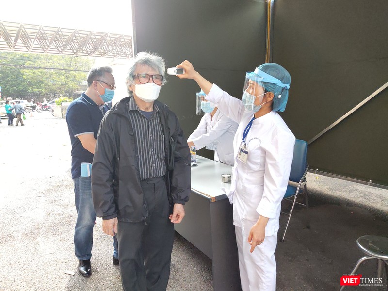 Nhân viên y tế đo nhiệt độ cho người dân khi đến bệnh viện (Ảnh: Minh Thúy) 