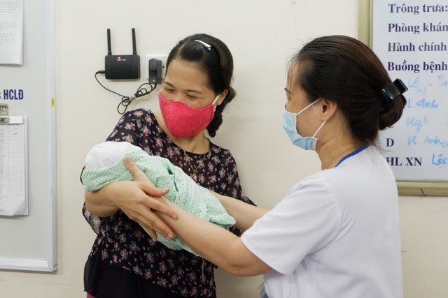 Điều dưỡng Loan trao bé An cho cán bộ Trung tâm bảo trợ xã hội (Ảnh: Lê Minh)