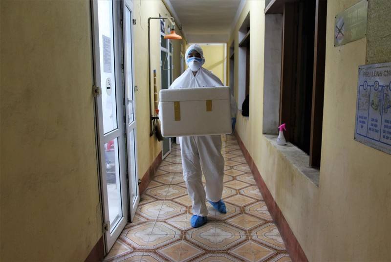 Nhân viên xét nghiệm bê thùng đựng mẫu bệnh phẩm vào phòng tách mẫu (Ảnh Kim Dung – Trung Sơn)
