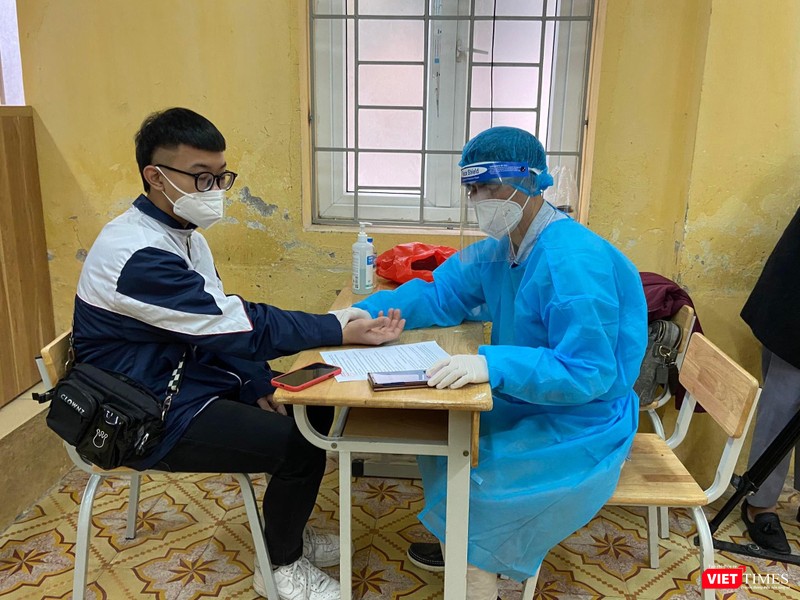 Nhân viên y tế kiểm tra sức khoẻ học sinh trước khi tiêm vaccine COVID-19 (Ảnh - Quang Hùng)
