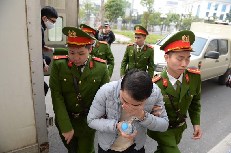 Bị cáo Vũ Hoàng Dũng (lao động tự do) lấy tay che mặt khi cảnh sát đưa vào phòng xét xử.