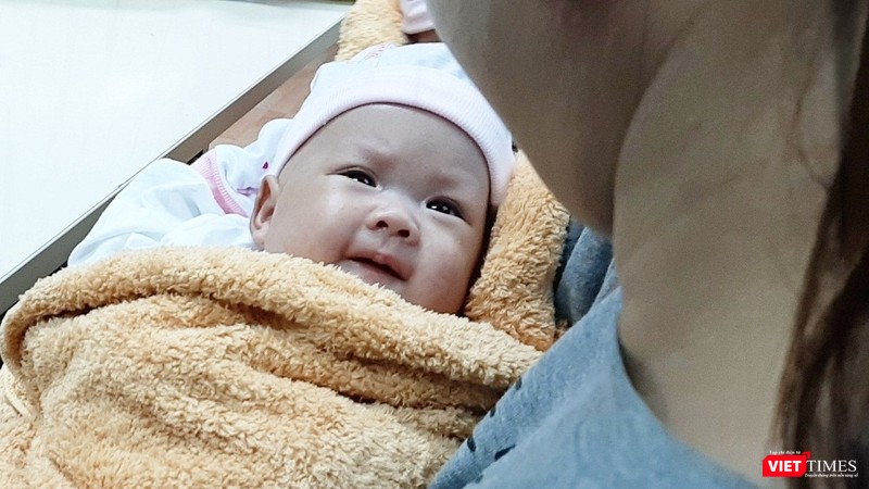 Bé Bình An mỉm cười , mở tròn mắt nhìn mẹ trong ngày xuất viện