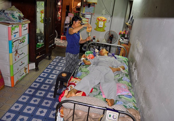 Bà Phạm Thị Thanh cho con trai bị tai nạn lao động ăn cháo bằng đường ống. Ảnh:Ngọc An. Bà Phạm Thị Thanh cho con trai bị tai nạn lao động ăn cháo bằng đường ống. Ảnh:Ngọc An.