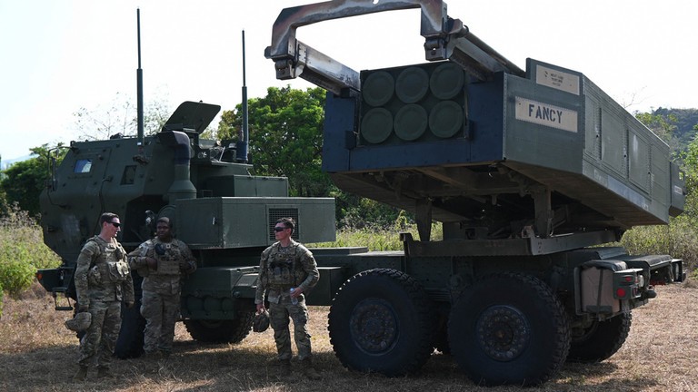 Các binh sĩ quân đội Mỹ đứng cạnh bệ phóng của hệ thống pháo phản lực cơ động cao (HIMARS) (Ảnh: AFP)