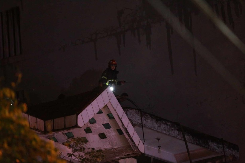 Lính cứu hỏa trèo lên nóc nhà kế bên để cứu hộ cứu nạn.