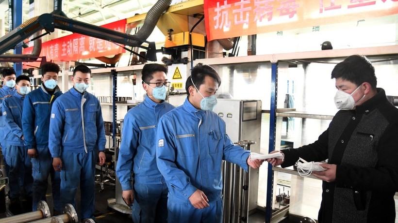 Công nhân một nhà máy nhận khẩu trang phòng hộ trước khi vào nhà máy sản xuất (Ảnh: Tân Hoa xã)