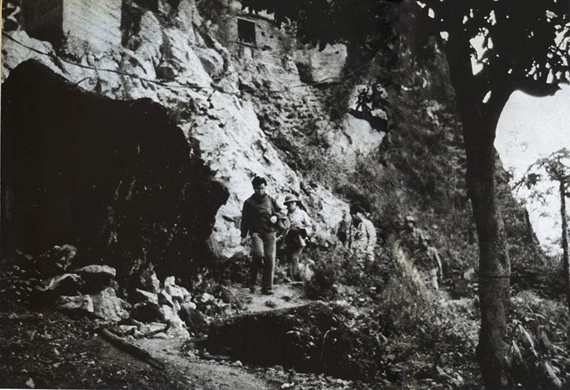 Nhà báo Takano Isao bước ra khỏi một hang động hướng về phía đỗ xe.