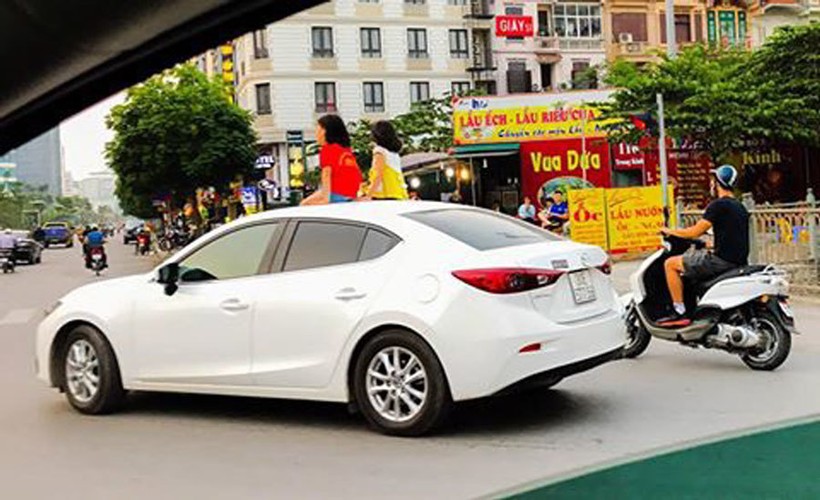 Nhiều phụ huynh cho phép con mở cửa sổ trời và thò đầu lên khi xe đang chạy, thậm chí cho ngồi hẳn lên cửa sổ trời để hóng gió, ngắm trời đất. (Ảnh: Dân trí)