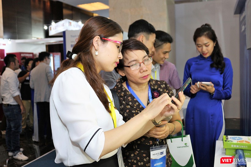 Nhân viên BIDV hướng dẫn khách tham quan cách sử dụng điện thoại để thanh toán hàng hóa qua mã QR code