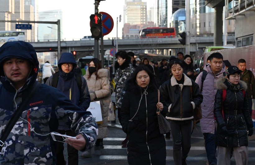 Người đi làm băng qua một con đường trong khu thương mại trung tâm của Bắc Kinh (ảnh: AFP)