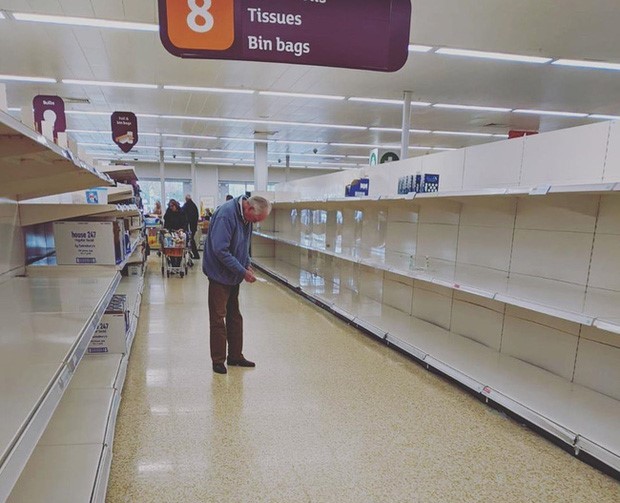 Cụ ông cúi đầu nhìn vào tờ ghi chú với dáng vẻ bất lực, cô độc, xung quanh ông là những kệ hàng trống trơn. Ảnh: Lauren Taylor, chụp tại siêu thị Sainsbury's, Luân Đôn (Anh).