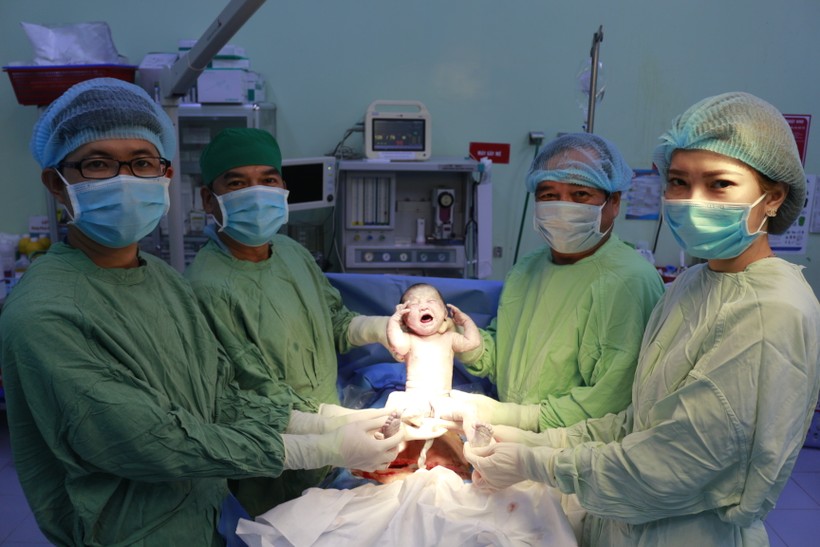 BS. Nguyễn Hữu Dự - Giám đốc BV Phụ sản TP. Cần Thơ (trong cùng bên phải) cùng ê kíp bác sĩ vui mừng chào đón bé trai chào đời trong thời khắc giao thừa. Cùng lúc đó, bé trai giơ hai tay như thay cho lời chúc mừng năm mới khiến ai nấy đều bật cười. Ảnh: BVCC