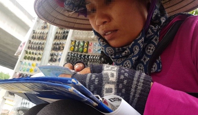 Người phụ nữ bán bảo hiểm xe máy bên vỉa hè. Ảnh: Zing