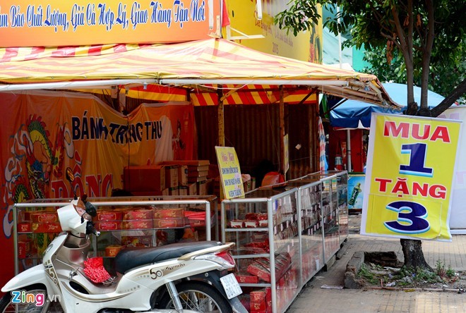 Treo bảng giảm giá mua 1 tặng 3 nhưng quầy bánh trung thu bên vòng xoay Âu Cơ - Lê Đại Hành vẫn vắng bóng khách. Nhân viên ngồi chơi bên trong quầy.
