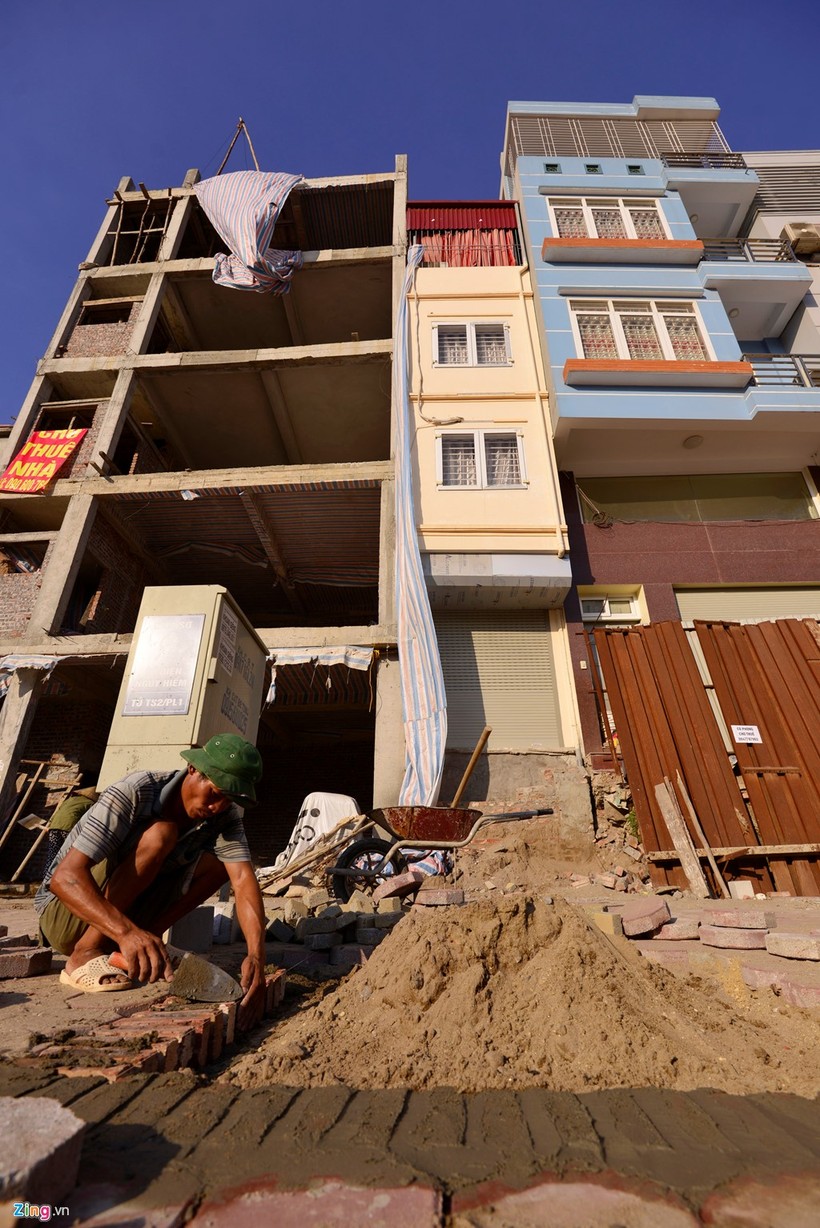 Ngôi nhà màu vàng có mặt tiền khoảng 2 m lọt thỏm giữa những ngôi nhà cao tầng còn lại.